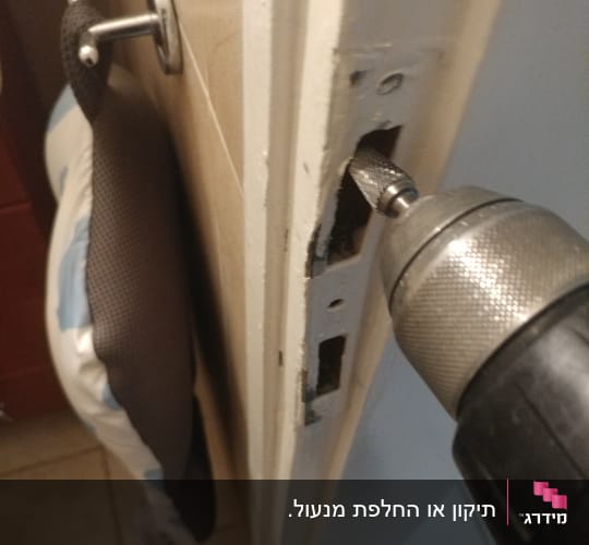 מקדחה חשמלית פועלת על דלת עם מנעול